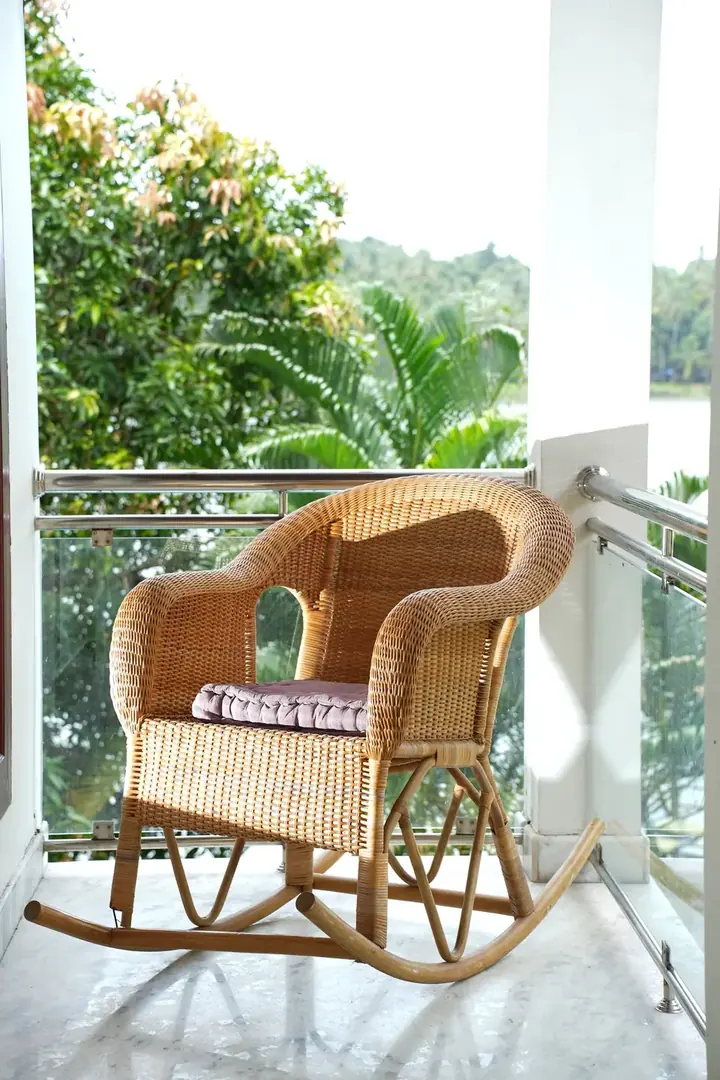 Cane rocking chair on the suite balcony looking over the garden and river